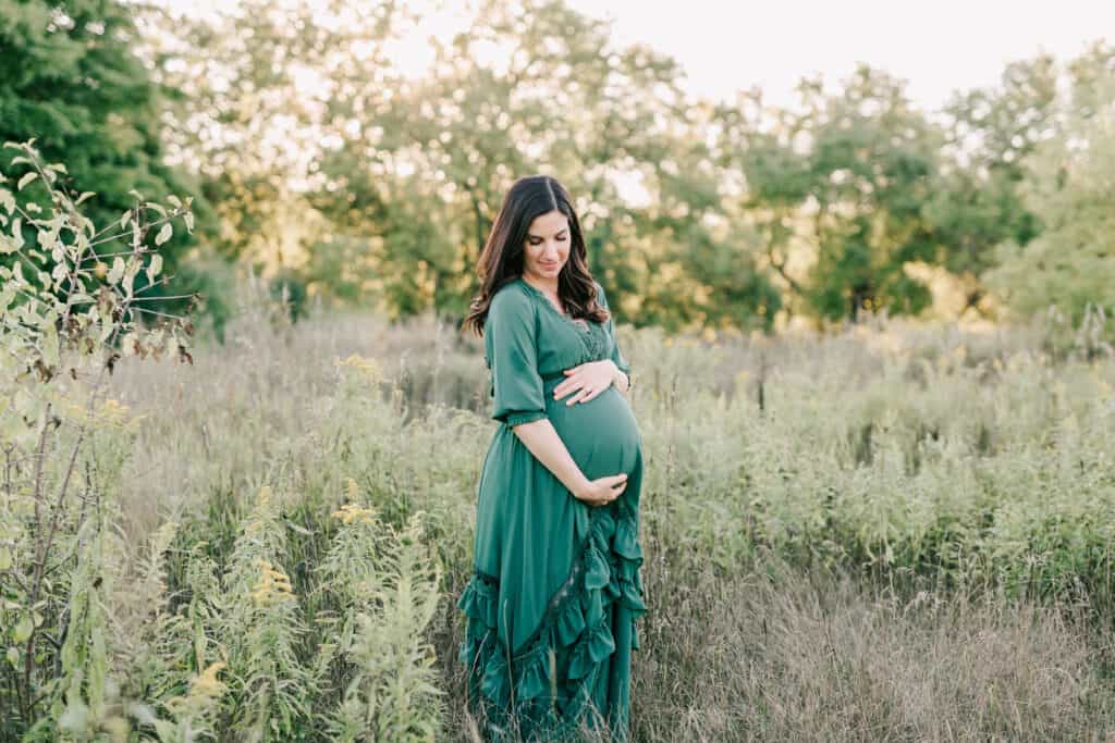 pregnant woman in a field wearing a green maternity gown