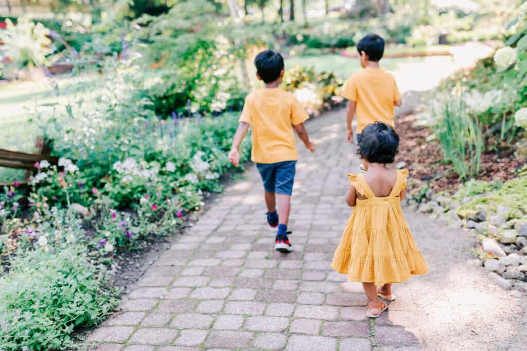 3 siblings in yellow walking through a park Mastermind Toys Guelph