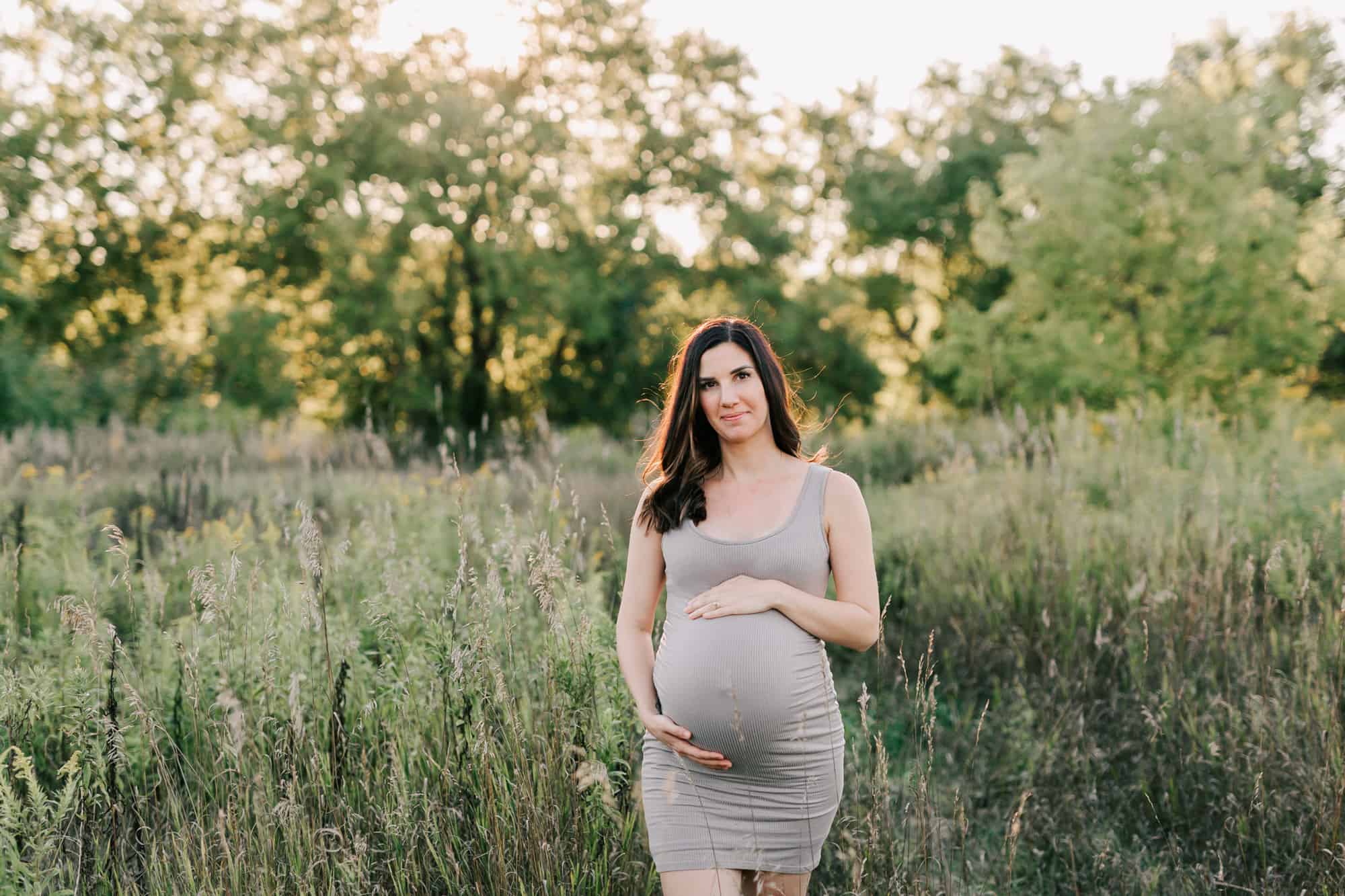 Owner of Skin Care Beauty Co., in Guelph ontario stands in a field during her maternity session