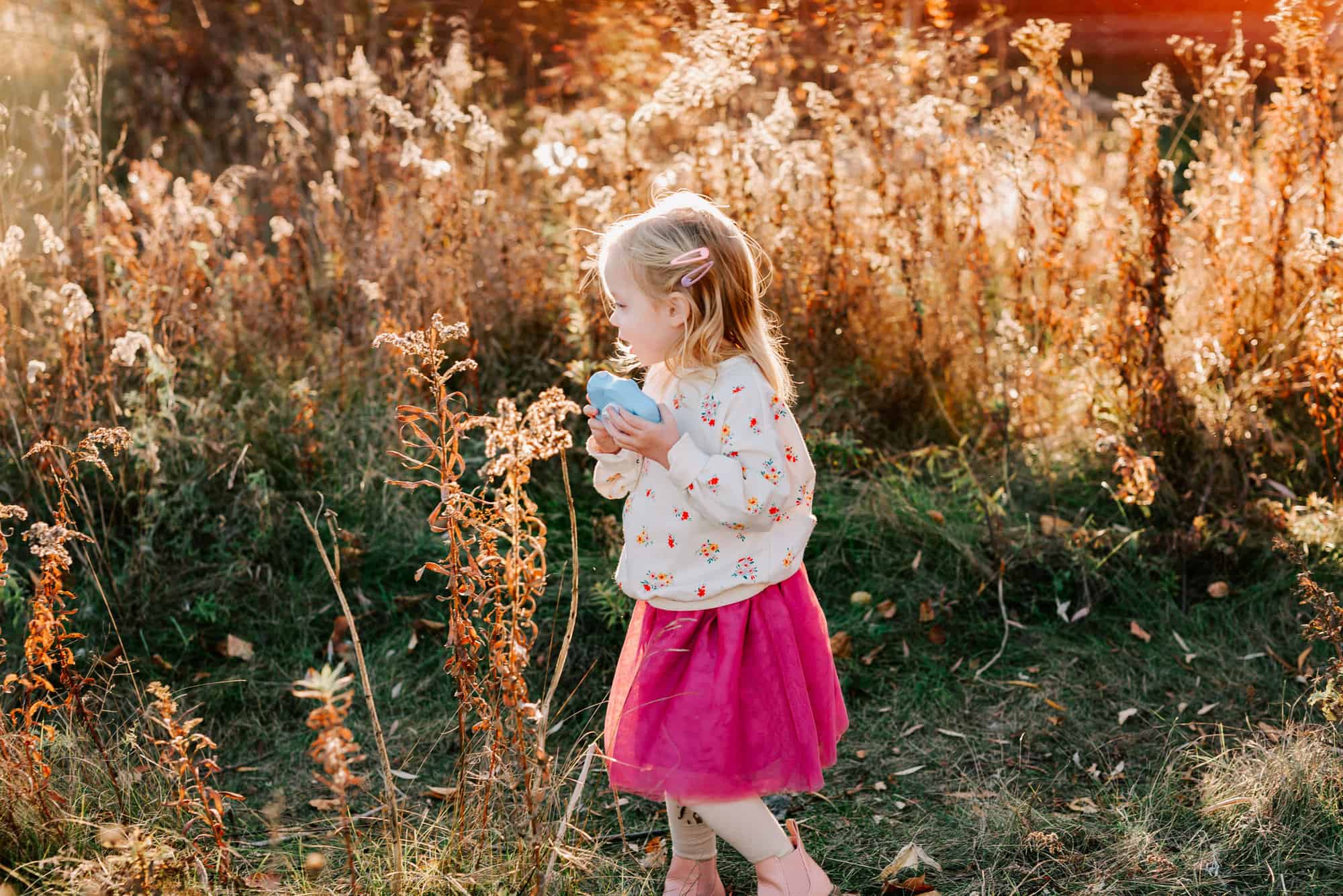 child exploring the field during her photoshoot with a camera from Simply Wonderful Toys, Guelph